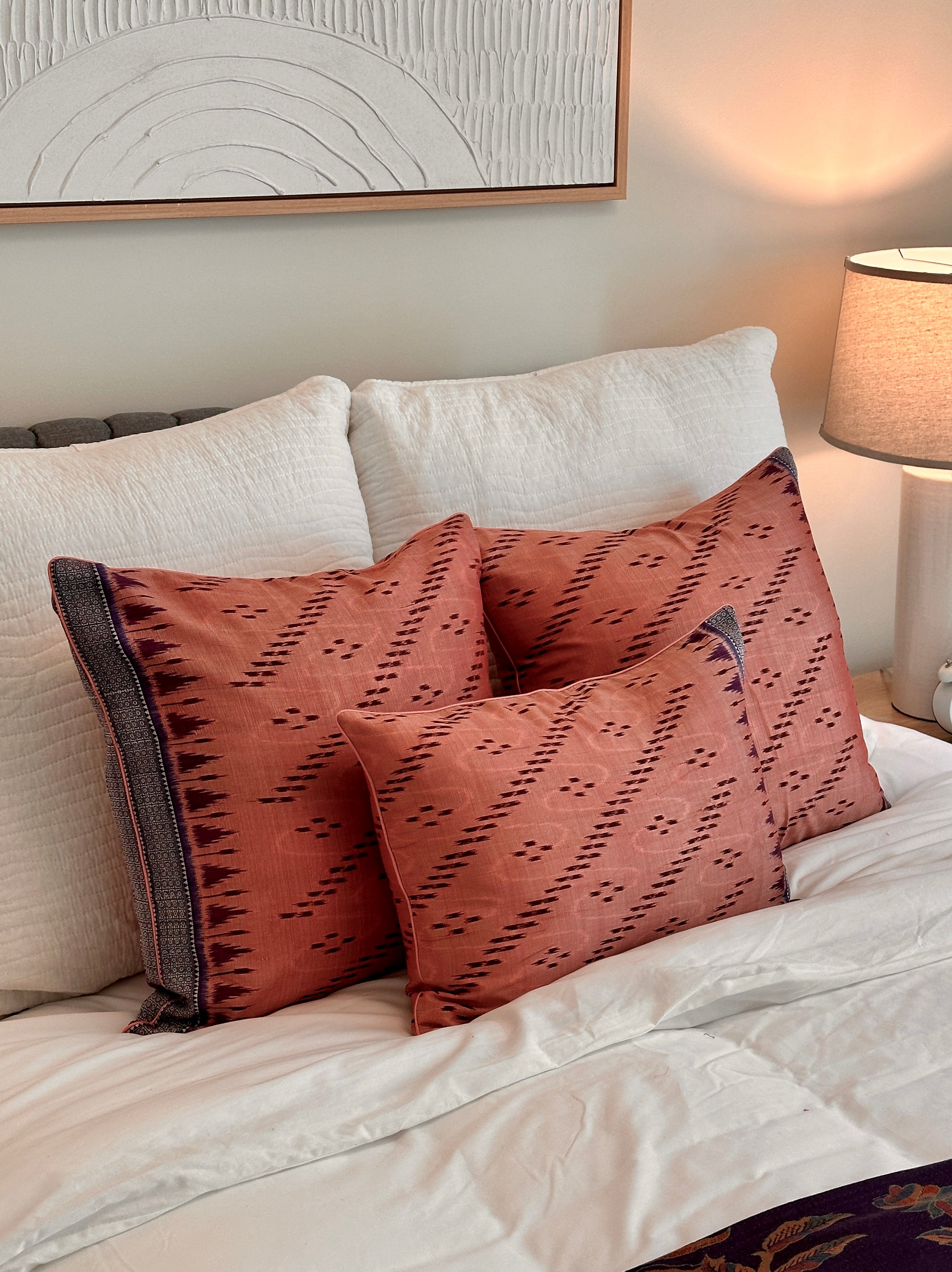 Handcrafted pillow cover made from vintage silk sari fabric in soft peach-pink, featuring ikat-inspired geometric patterns. The 20x20 pillow is one-of-a-kind, showcasing traditional silk weaving techniques with intricate details and luxurious texture
