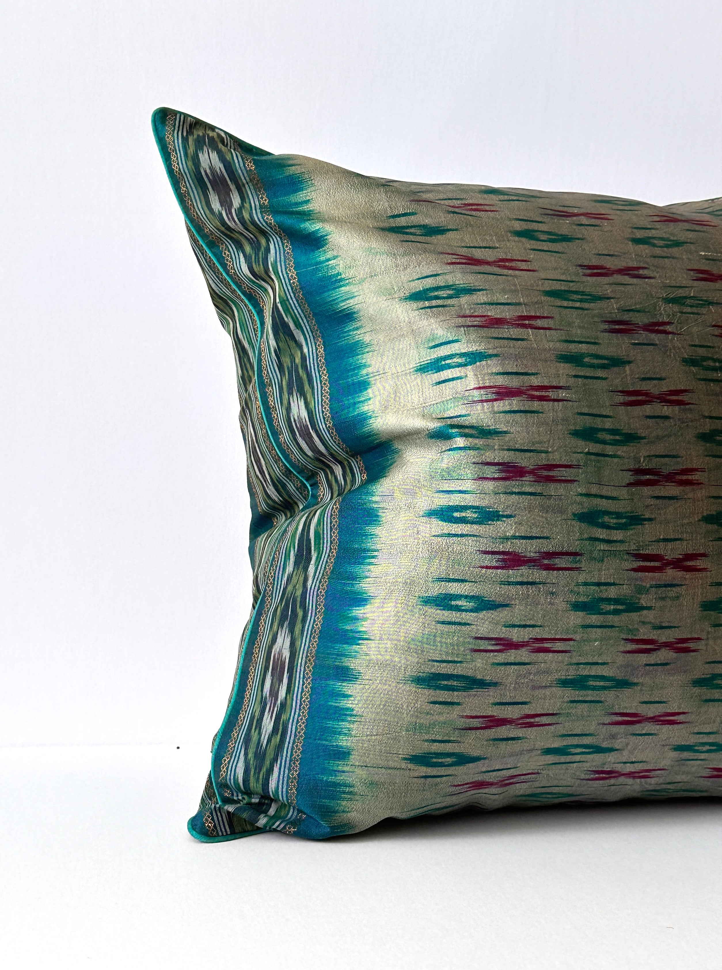 A handcrafted 20x20 pillow cover made from vintage silk fabric, featuring a vibrant ikat pattern in shades of blue and pink. The cushion showcases a unique blend of traditional weaving techniques with a modern, bold color palette.