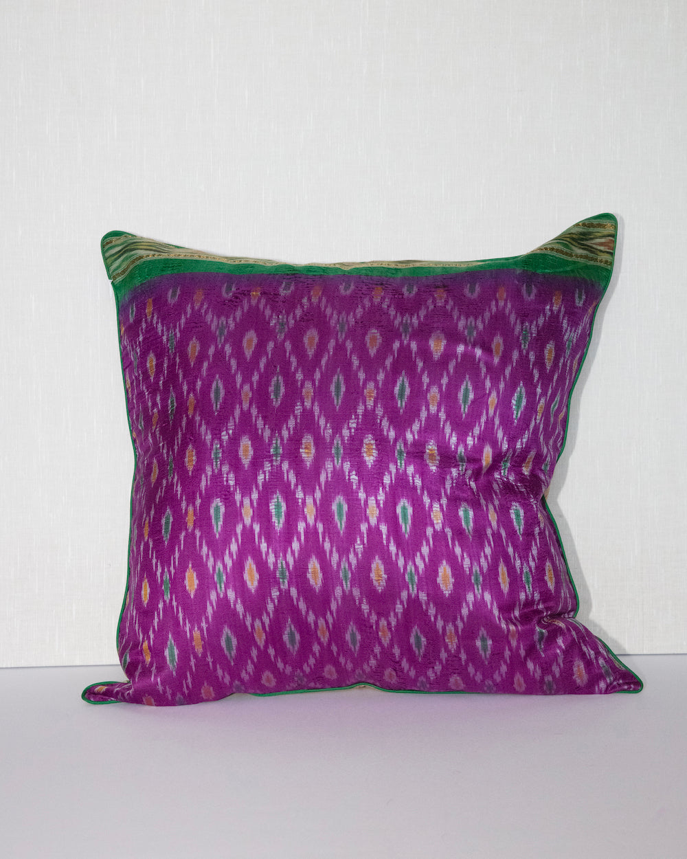 Handcrafted pillow cover made from vintage silk sari fabric in dewberry-pink, featuring ikat-inspired geometric patterns. The 20x20 pillow is one-of-a-kind, showcasing traditional silk weaving techniques with intricate details and luxurious texture