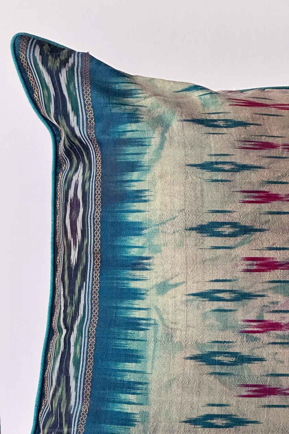 A handcrafted 20x20 pillow cover made from vintage silk fabric, featuring a vibrant ikat pattern in shades of blue and pink. The cushion showcases a unique blend of traditional weaving techniques with a modern, bold color palette.