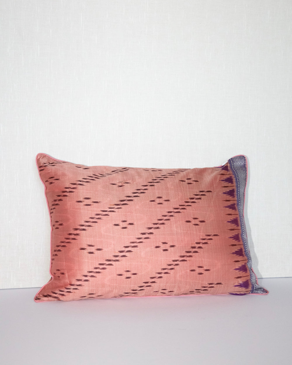 Handcrafted pillow cover made from vintage silk sari fabric in soft peach-pink, featuring ikat-inspired geometric patterns. The 12x20 pillow is one-of-a-kind, showcasing traditional silk weaving techniques with intricate details and luxurious texture