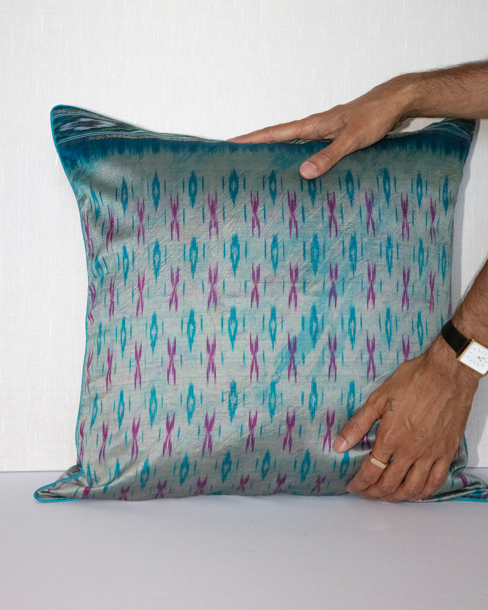 A handcrafted 20x20 pillow cover made from vintage silk fabric, featuring a vibrant ikat pattern in shades of blue and pink. The cushion showcases a unique blend of traditional weaving techniques with a modern, bold color palette.