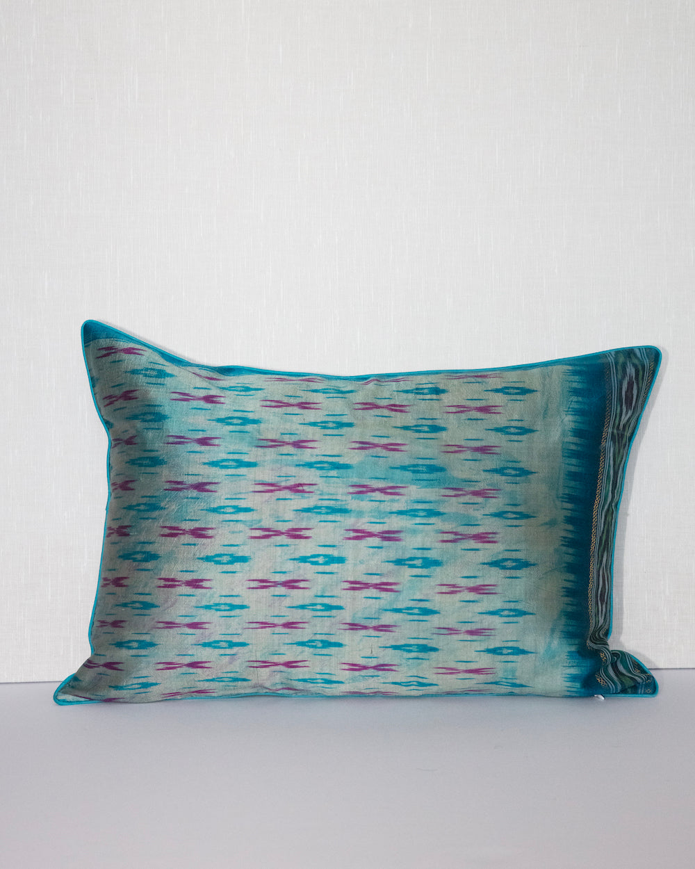 A handcrafted 20x20 pillow cover made from vintage silk fabric, featuring a vibrant ikat pattern in shades of blue and pink. The cushion showcases a unique blend of traditional weaving techniques with a modern, bold color palette.