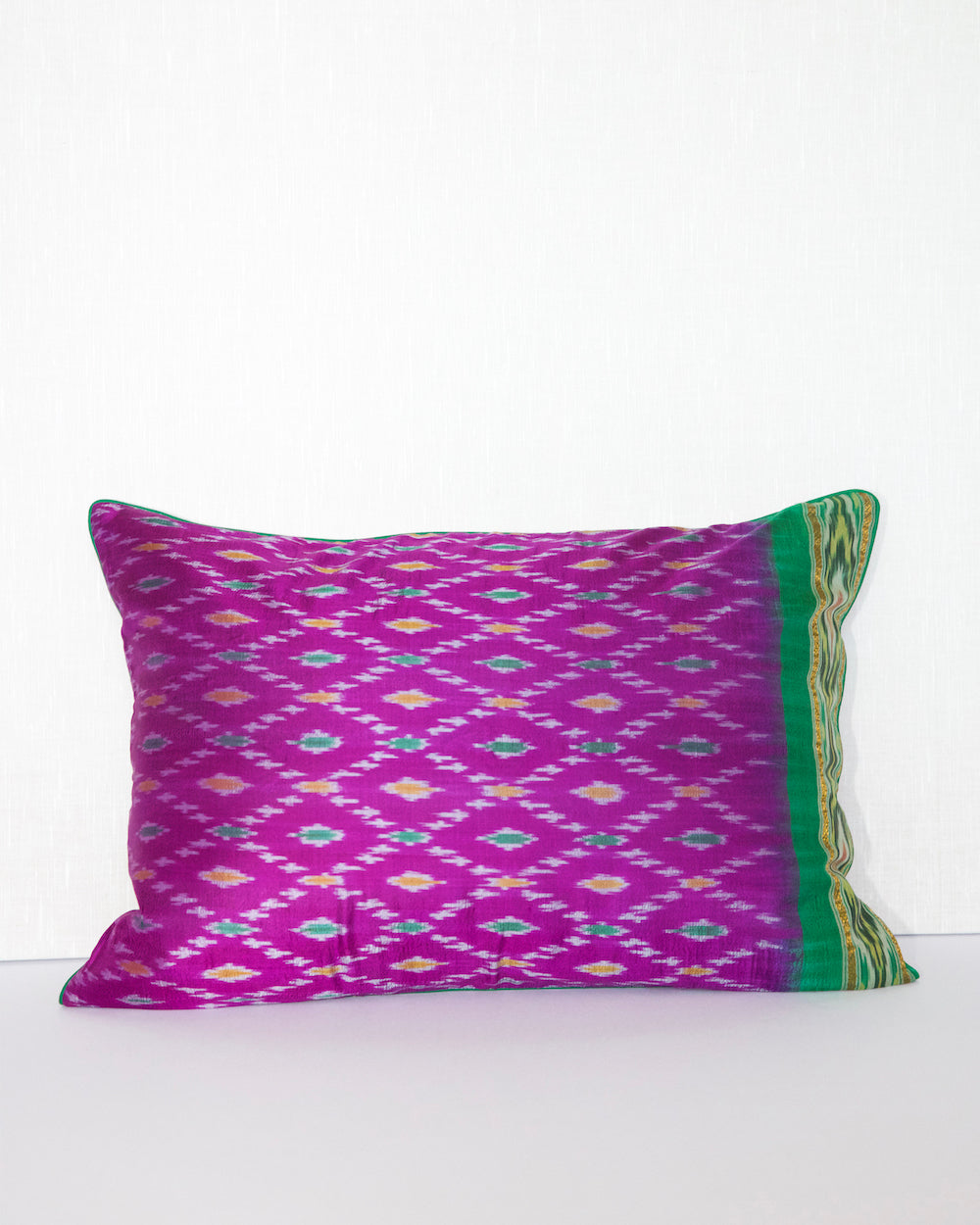 Handcrafted pillow cover made from vintage silk sari fabric in dewberry-pink, featuring ikat-inspired geometric patterns. The 20x20 pillow is one-of-a-kind, showcasing traditional silk weaving techniques with intricate details and luxurious texture