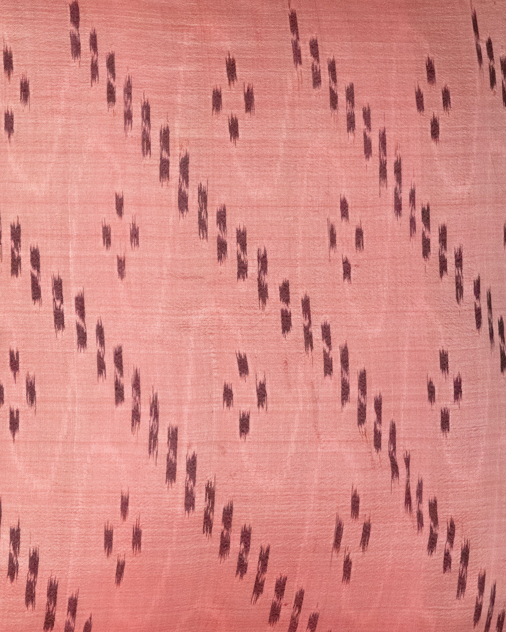 Handcrafted pillow cover made from vintage silk sari fabric in soft peach-pink, featuring ikat-inspired geometric patterns. The 20x20 pillow is one-of-a-kind, showcasing traditional silk weaving techniques with intricate details and luxurious texture