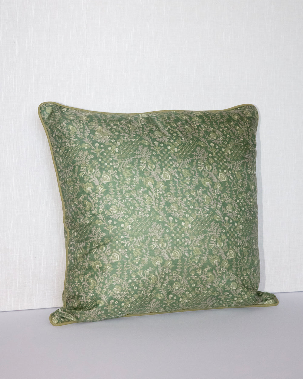 A handcrafted 18x18 pillow cover in a soft green shade, featuring delicate floral and vine patterns in a subtle cream color. The intricate detailing and smooth fabric give the cushion an elegant, nature-inspired look.