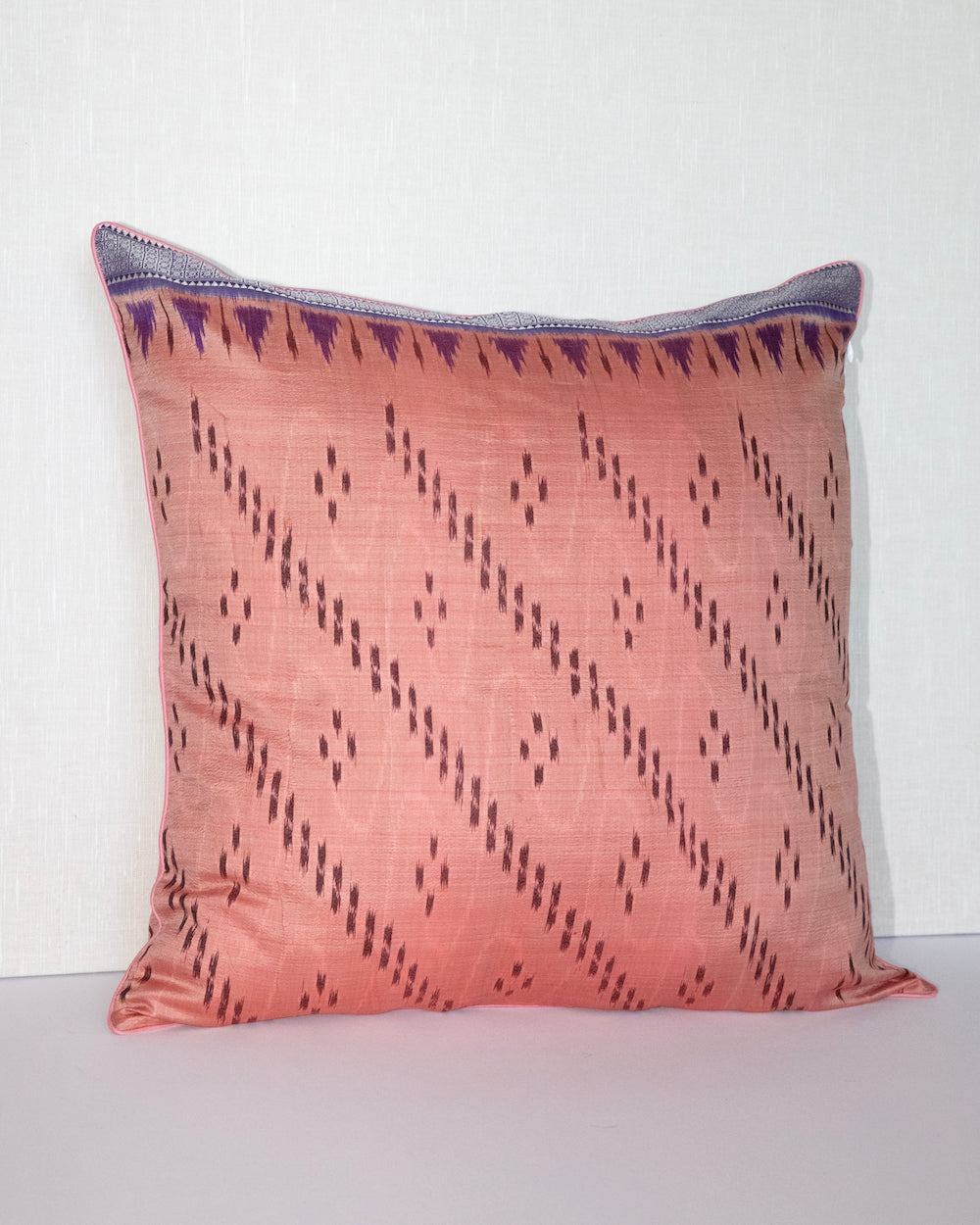 Handcrafted pillow cover made from vintage silk sari fabric in soft peach-pink, featuring ikat-inspired geometric patterns. The 20x20 pillow is one-of-a-kind, showcasing traditional silk weaving techniques with intricate details and luxurious texture