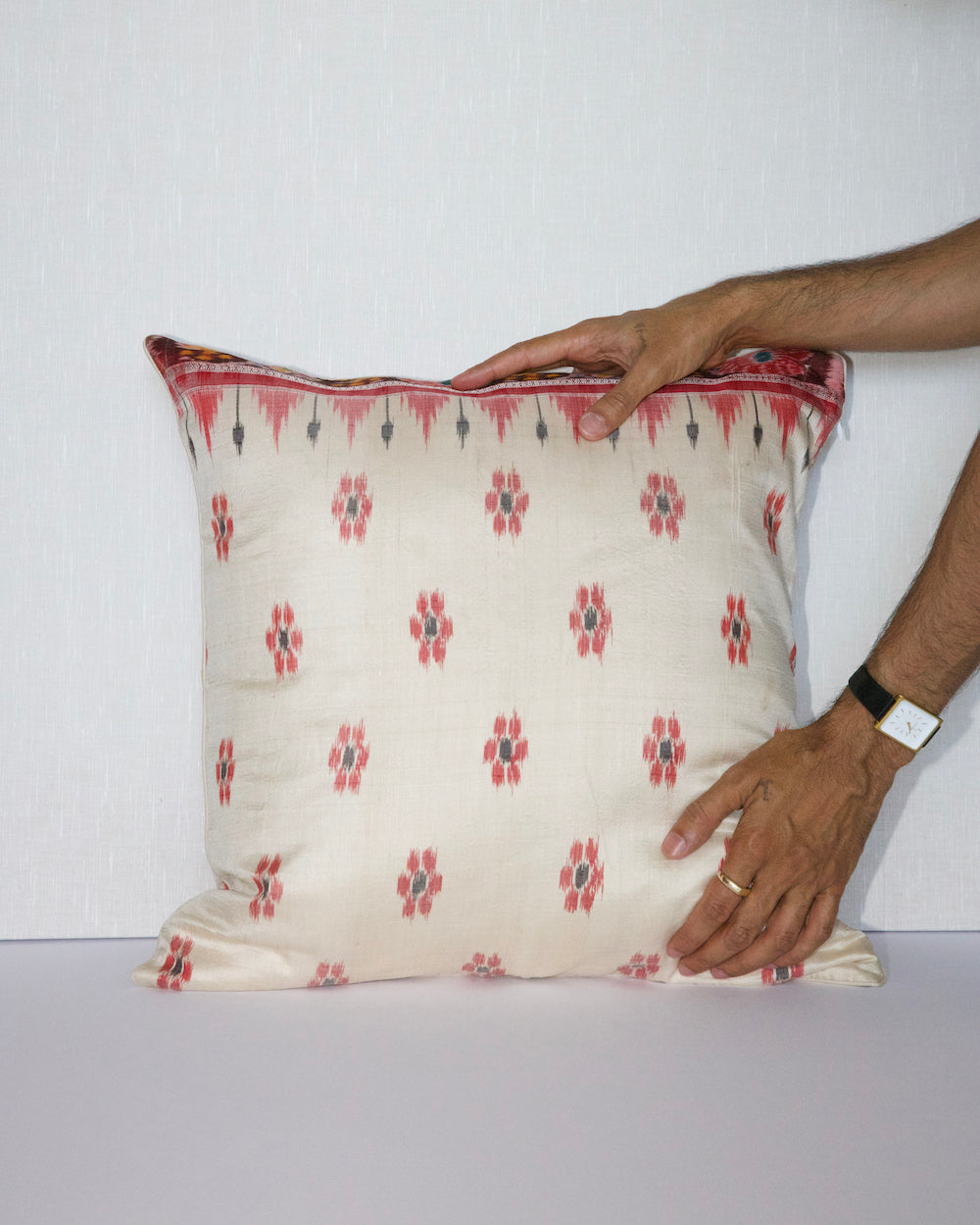 A handcrafted 20x20 pillow cover made from vintage silk sari fabric, featuring a cream background with red and black ikat-inspired floral patterns. The cushion is bordered with a subtle red and black design, showcasing intricate silk weaving techniques.